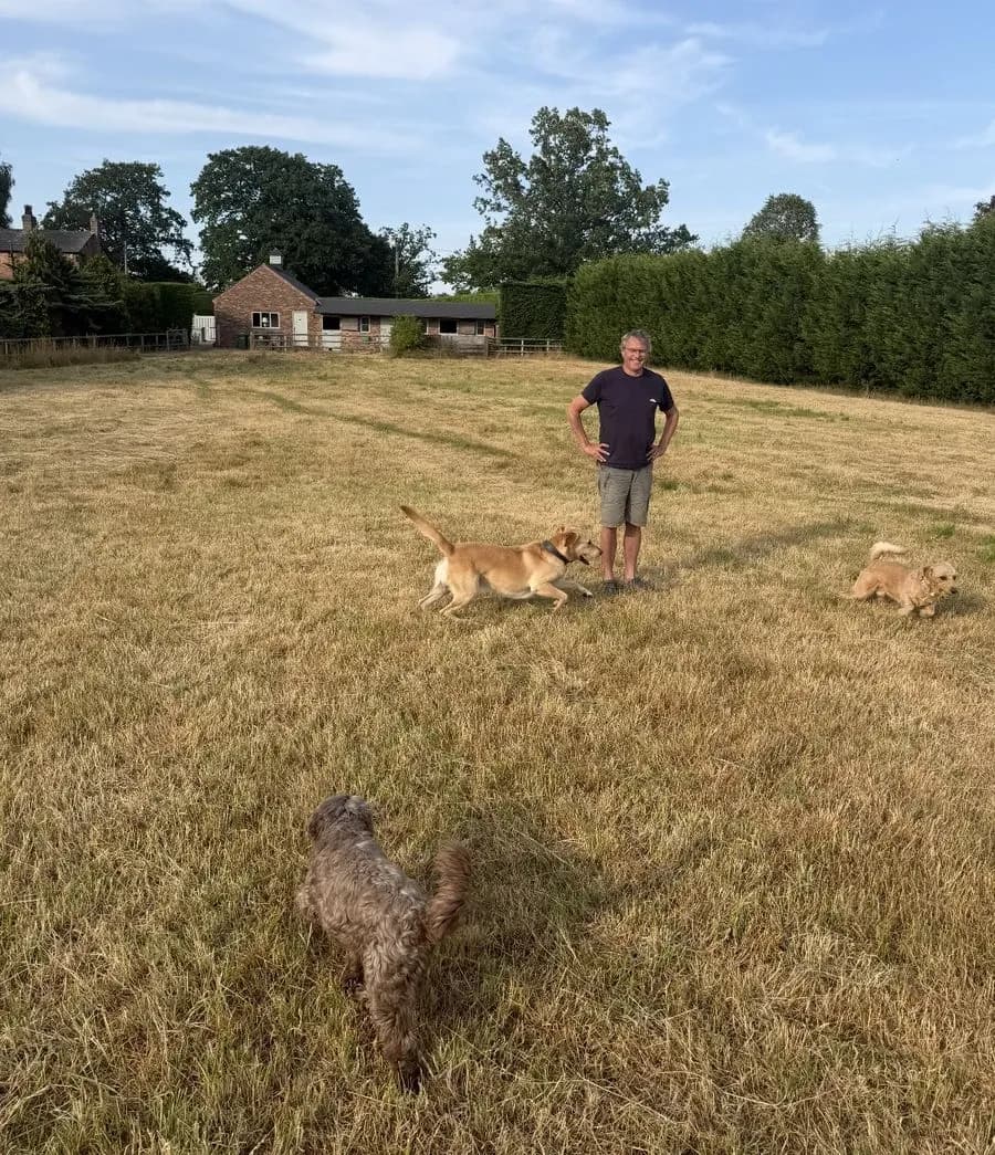 Andy in the field with three dogs running rings round him